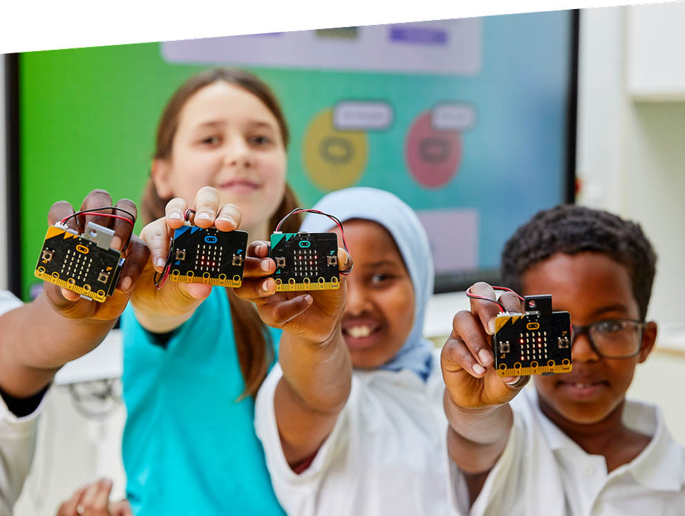 children in class smiling and holding micro:bits